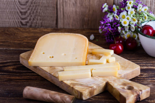 Traditional Dutch semi hard cheese served with sweet cheeries Traditional Dutch semi hard cheese served with sweet cheeries on rural table with summer wild flower gouda cheese stock pictures, royalty-free photos & images
