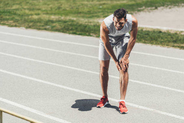 istock suffering young runner with leg injury standing on running track 995299232