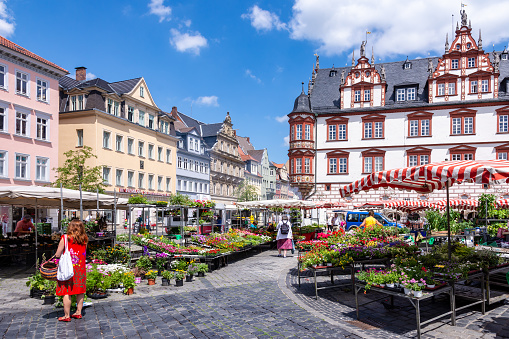 People at a market with flowers and food, located at the historic marketplace of Coburg, Germany on June 20, 2018. Foto taken from Marktplatz with view to the north