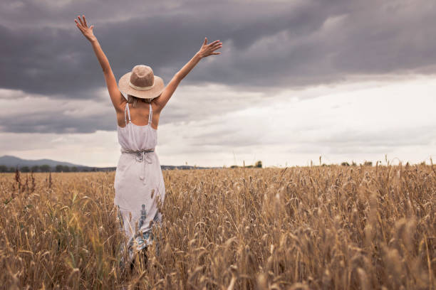 istock Girl standing in wheat field 995305932