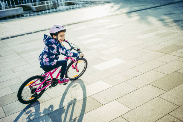 istock Young Girl Enjoying Riding Bicycle on Town Square 995309904