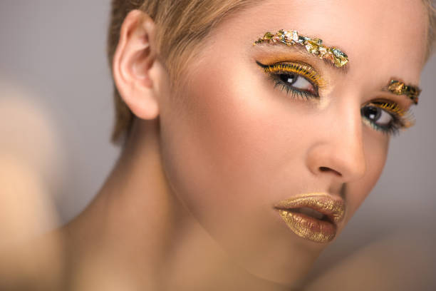 istock attractive woman with colored bright glitter on face looking at camera isolated on grey 995312796