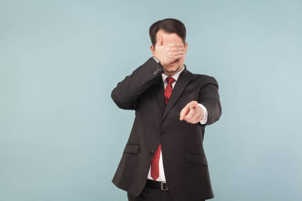 istock Man in suit closed eyes and pointing finger at camera 995312964