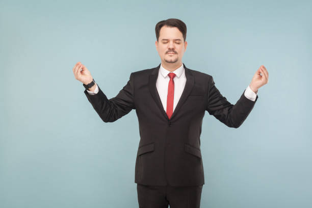 istock Business man closed eyes, standing and doing yoga pose 995313076