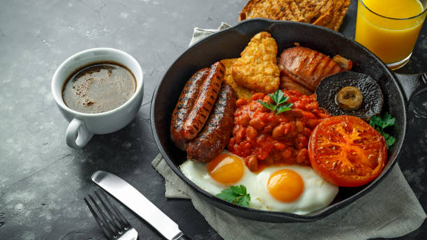 완전 한 영어 아침 식사 베이컨, 소시지, 계란, 구운된 콩, 감자와 버섯 소박한 프라이팬, 팬. 컵 커피, 오렌지 주스 - breakfast bacon eggs toast 뉴스 사진 이미지