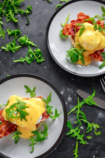 istock Eggs Benedict on english muffin with crispy bacon, wild rocket salad and hollandaise sauce 995319904