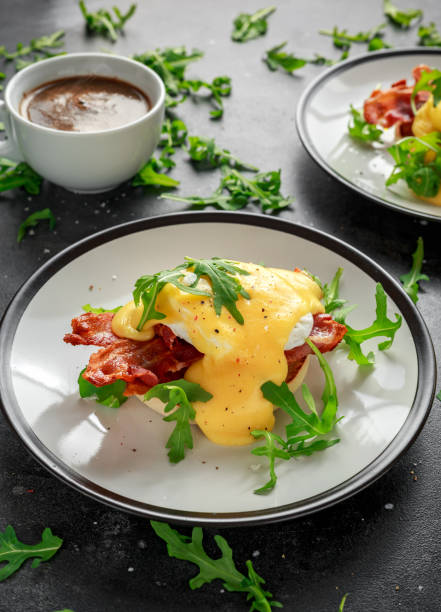 istock Eggs Benedict on english muffin with crispy bacon, wild rocket salad and hollandaise sauce 995319932