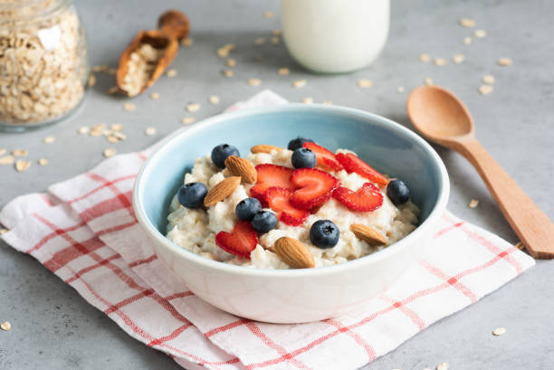 porridge di farina d'avena con fragole, mirtilli e mandorle - oatmeal heat bowl breakfast foto e immagini stock