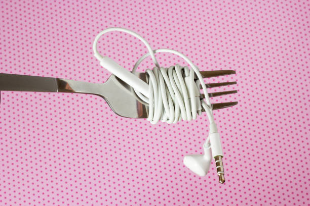 istock White headphones and fork on a pink background with polka dotsd, close-up 995329416