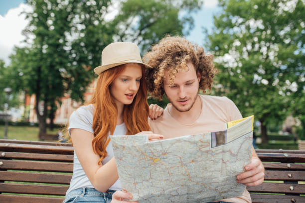 istock Young couple of tourists reading a map 995343254
