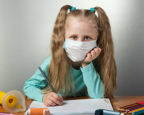 istock Little sick girl in protective bandage draws, on gray background 995348770