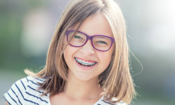 portrait de jeune fille souriante heureuse avec bretelles dentaires et les lunettes. - dentists chair people care medical equipment photos et images de collection