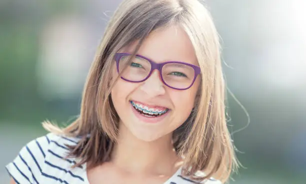 Portrait of happy smiling girl with dental braces and glasses.