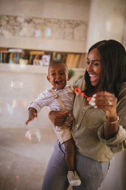 istock Happy mother and excited boy playing with bubbles at home 995350516