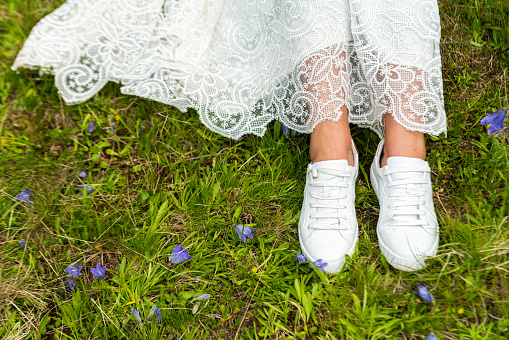 Bride's feet in sneakers on green background.