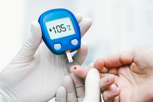 Doctor making blood sugar test in clinic for diabetes stock photo