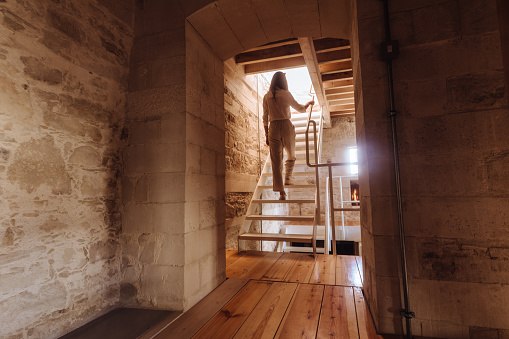 Woman walking up modern wooden staircase in village stone built chalet in the countryside