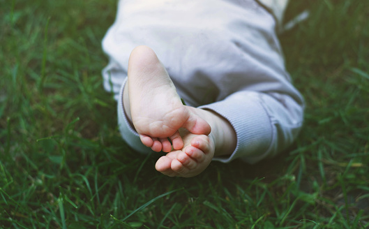 The Cute feet of baby in the green grass.