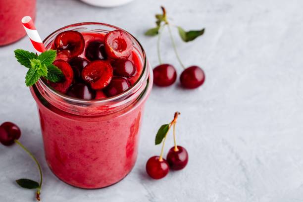 frullato di ciliegia in bicchiere con foglie di menta e bacche fresche - healthy lifestyle cranberry healthy eating milk shake foto e immagini stock