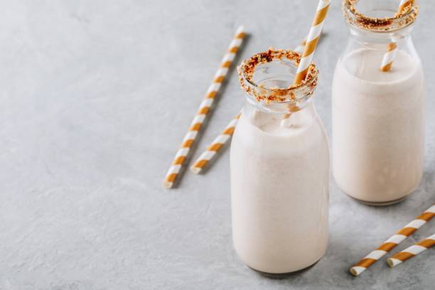 istock Vanilla milkshake in glass bottles on a gray background 995359674