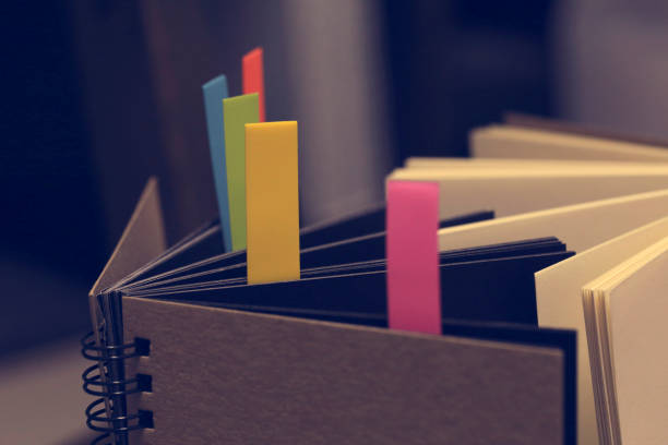 istock Closeup shot of notebook with color note tab. Notebook with colors note tab on wooden table background, Vintage picture tone. 995364690