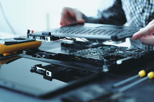 electronic renovation in repair shop. engineer disassembling broken laptop removing keyboard