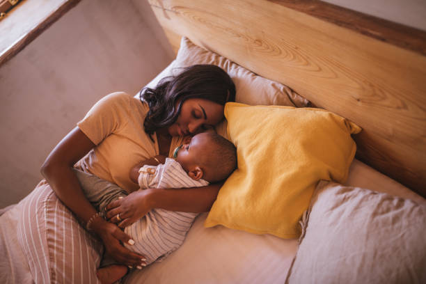 giovane madre che abbraccia il bambino e dorme a letto - 12 23 mesi foto e immagini stock