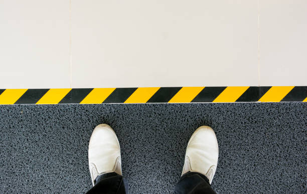 istock Mind your step line on the floor with men feet standing at entrance gate background 995396548