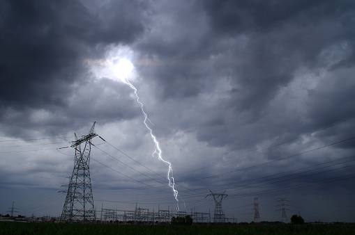 Lightning storm on electric tower. Dramatic sky and thunderstorm over energy station.