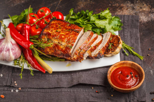 istock Roasted pork with thyme, rosemary, garlic and tomato sauce on a white dish, dark background, copy space. 995402146