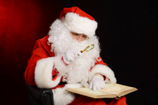 istock Santa Claus holding magnifying glass and looking at map 995405436