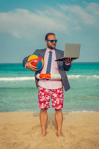Portrait of funny businessman on the beach. Man having fun by the sea. Summer vacation and travel concept