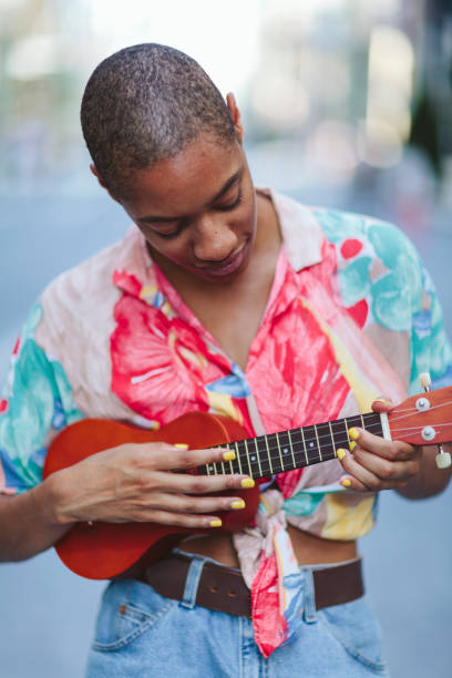 istock Young woman playing ukulele in street 995419564
