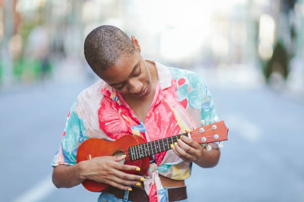 istock Young woman playing ukulele in street 995419610