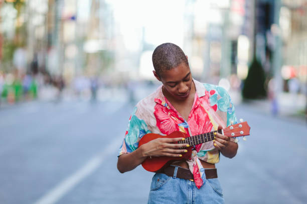 istock Young woman playing ukulele in street 995419738