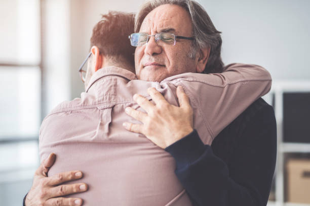 Son hugs his own father Son hugs his own father adult offspring photos stock pictures, royalty-free photos & images