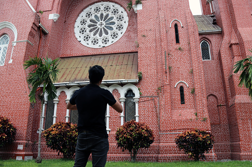 Behind of the man standing in front of the main building of church and church tower at cathedral of the holy trinity, the church of the province of Myanmar.