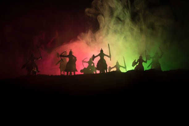 istock Medieval battle scene with cavalry and infantry. Silhouettes of figures as separate objects, fight between warriors on dark toned foggy background. Night scene. 995434228