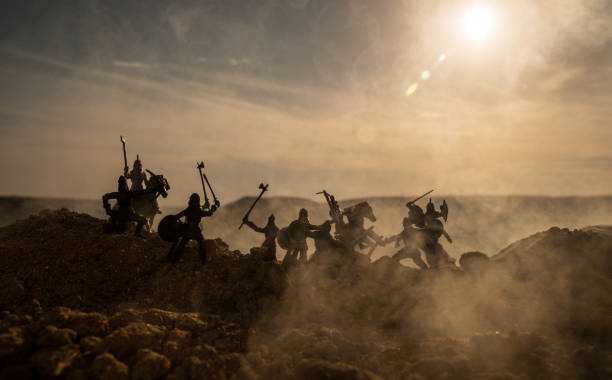 istock Medieval battle scene with cavalry and infantry. Silhouettes of figures as separate objects, fight between warriors on sunset foggy background. 995434246