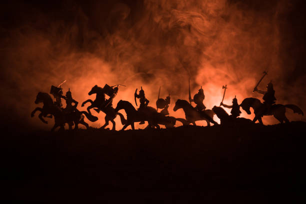 istock Medieval battle scene with cavalry and infantry. Silhouettes of figures as separate objects, fight between warriors on dark toned foggy background. Night scene. 995434248