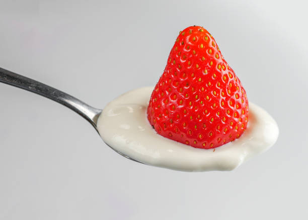 istock Spoon with strawberry in sour cream closeup 995439910
