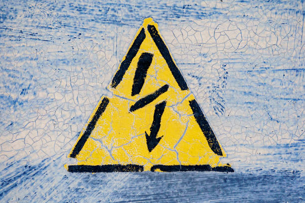 istock Old risk of electric shock triangle sign on light grey weathered cracked background 995440402