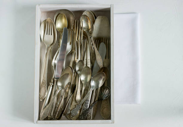 Vintage silver cutlery in a white wooden box on a white table. Rustic style.