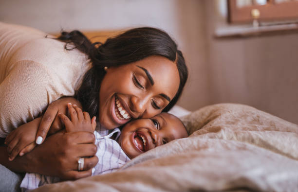 istock Affectionate mother having fun hugging smiling baby boy in bed 995463126