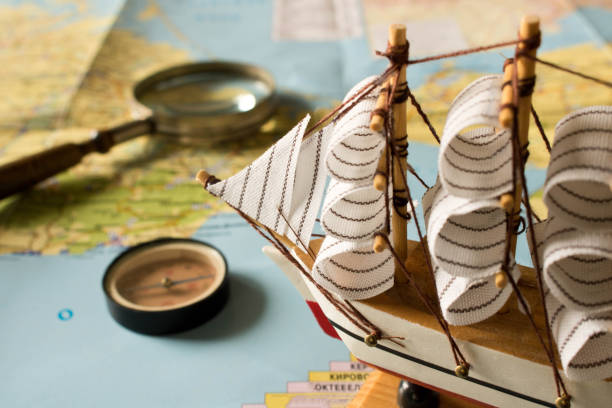 istock Model sailboat, compass and magnifying glass on map background. Travel concept 995463362