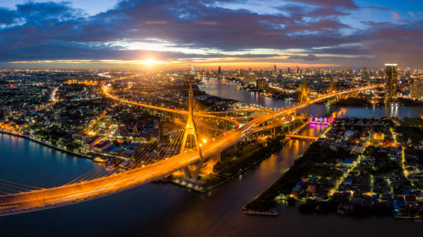 vista aérea da ponte de suspensão bhumibol atravessar o rio chao phraya, na cidade de banguecoque, com carro na ponte no céu do sol e nuvens em bangkok tailândia. - bridge bangkok suspension bridge river - fotografias e filmes do acervo