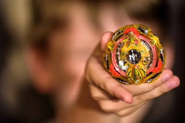 Photo of Popular kids toys. Little caucasian boy demonstrated Beyblade