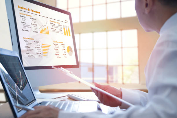 Business performance analysis Businessman analysing on business performance on desktop and notebook computer with orange-gold graphs. cash flow photos stock pictures, royalty-free photos & images