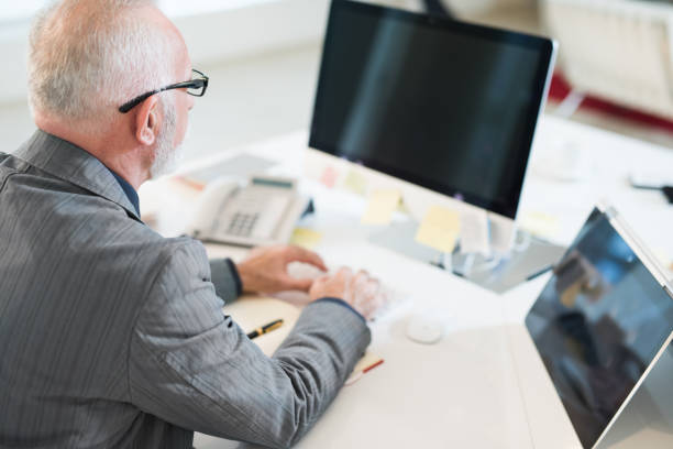 istock Mature businessman working in his office rear view. 995485578