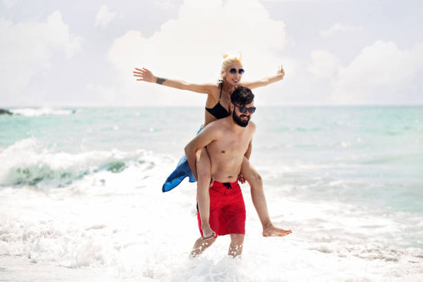 istock Piggyback on beach. Young happy couple at tropical beach. 995485924